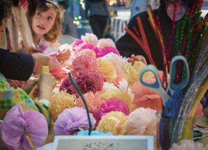 An image of a child looking at a bouquet, Paper Flower Making Workshop. Pom Pom Factory
