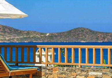 An image of a patio with a chair and umbrella, Five Star Greek Spa Getaway. Elounda Mare