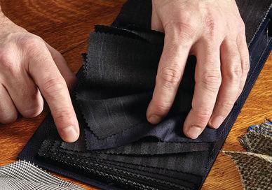 An image of a man's hands removing a piece of fabric, Create a Fully Bespoke Groom or Groomsman Suit. Stowers London